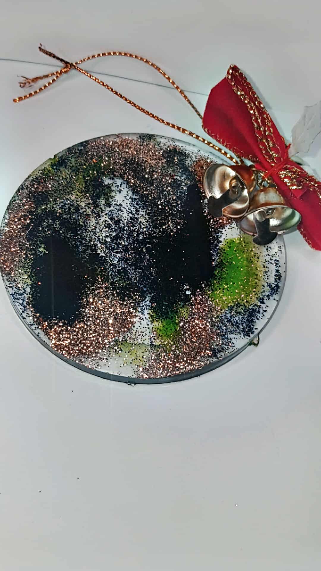 Decorative round ornament with bell and ribbons on a white background