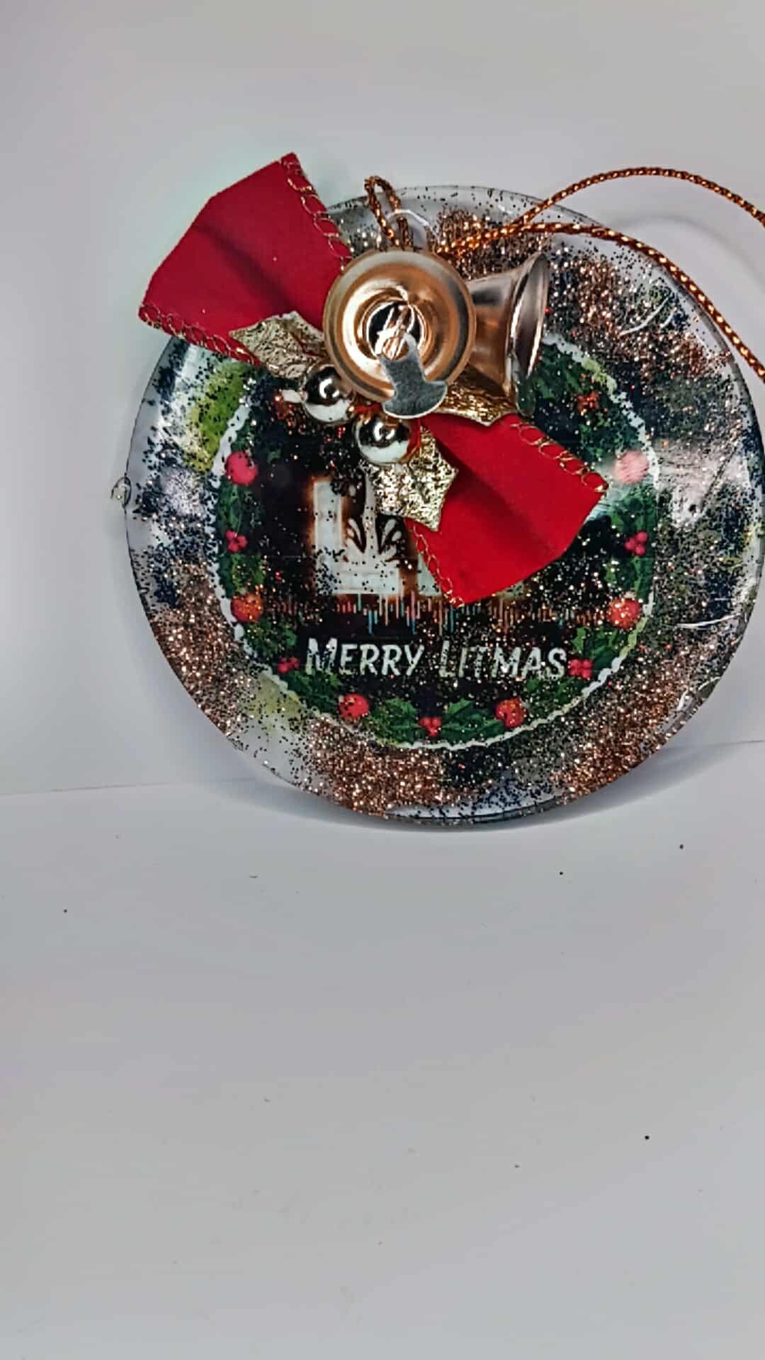 Decorative Christmas ornament with a wreath design, red bow, and 'Merry Litmas' text on a white background.