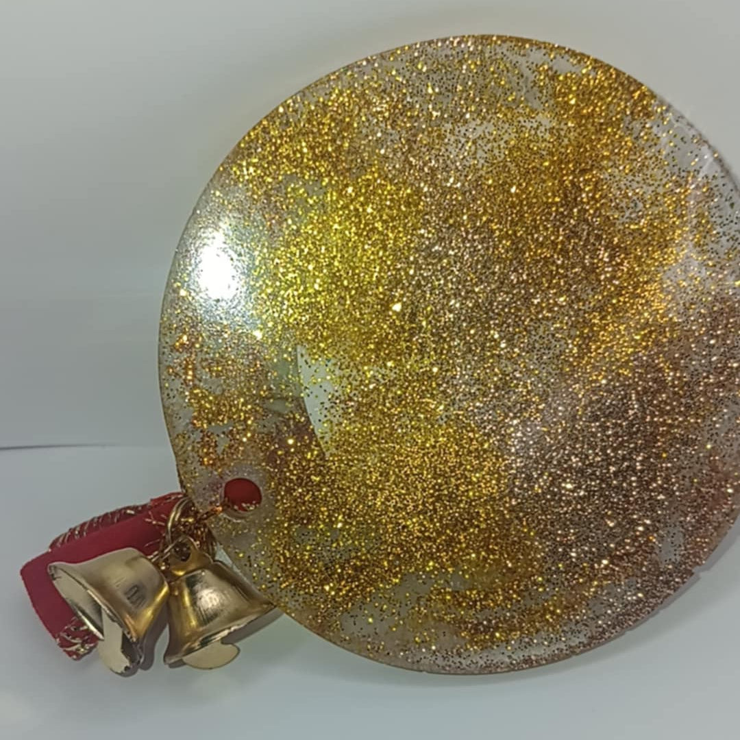 Gold glittery Christmas ornament with a bell on a white background