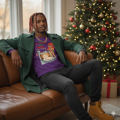Man sitting on a brown couch wearing a green coat and purple graphic t-shirt in a room with a Christmas tree.