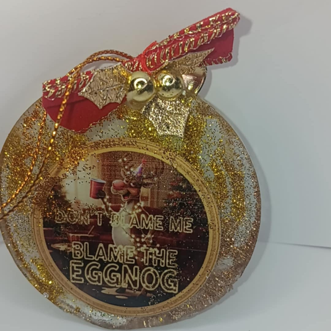 Decorative Christmas ornament with gold glitter and red ribbon on a white background