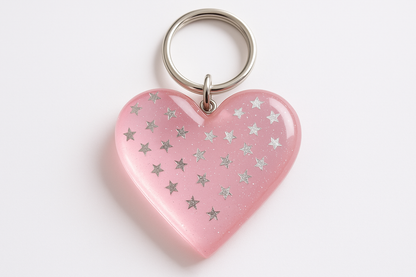 resin keychain that is light pink color and it has sliver stars in side of the heart shape resin keychain